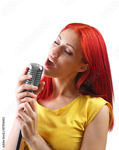 Beautiful young woman singing with microphone isolated on white