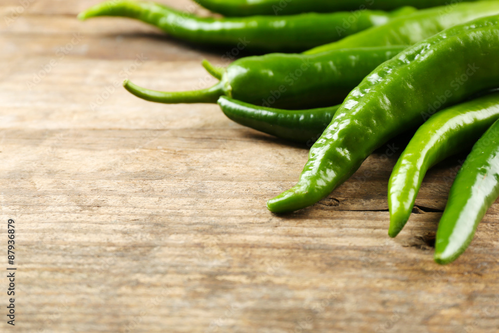Green hot peppers on wooden table close up Green hot peppers on wooden table close up