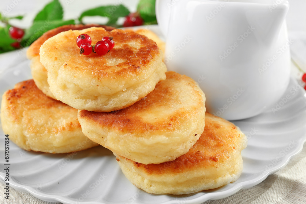 Fritters of cottage cheese with red currant in plate on table, closeup