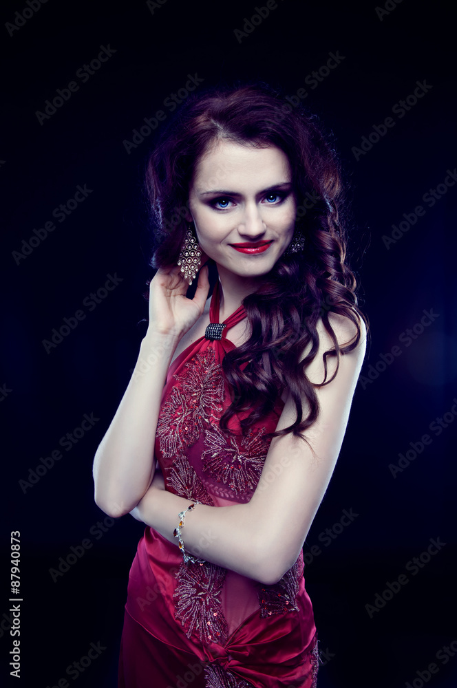 Beautiful redheaded woman with long curly hair in red evening dr Beautiful redheaded woman with long curly hair in red evening dr