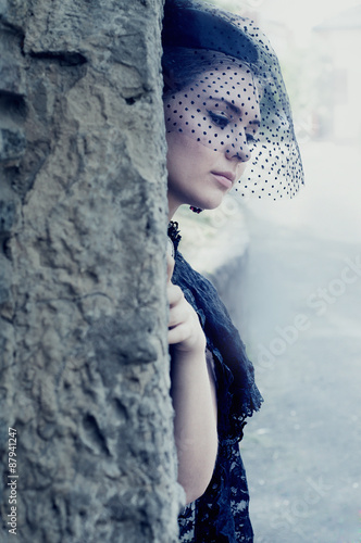 Mysterious woman in dark veil hiding in the cave