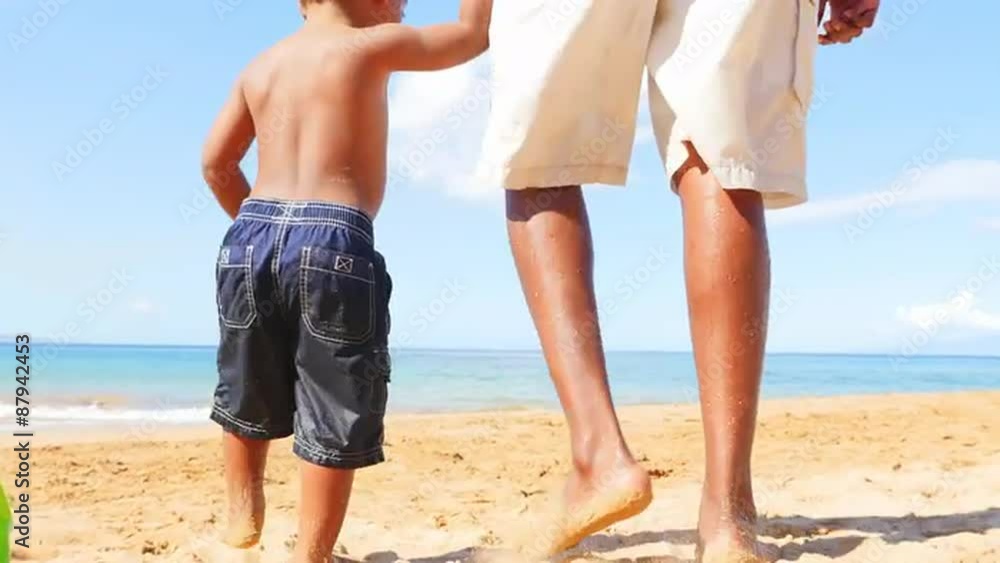 Black toddler walking on the beach holding hands with his father. Black toddler walking on the beach holding hands with his father.