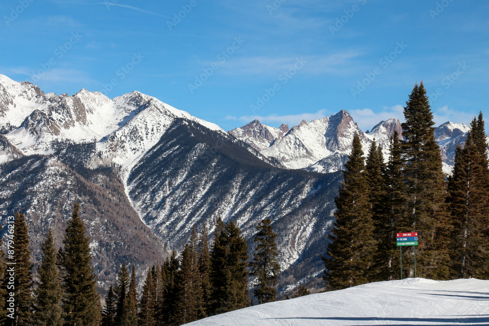 Ski hill with large mountain peaks and red, green and blue sign