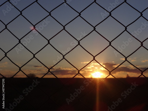 Puesta del sol a través del alambrado