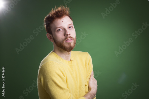 Portrait of ginger beautiful male model, laying in green grass. photo