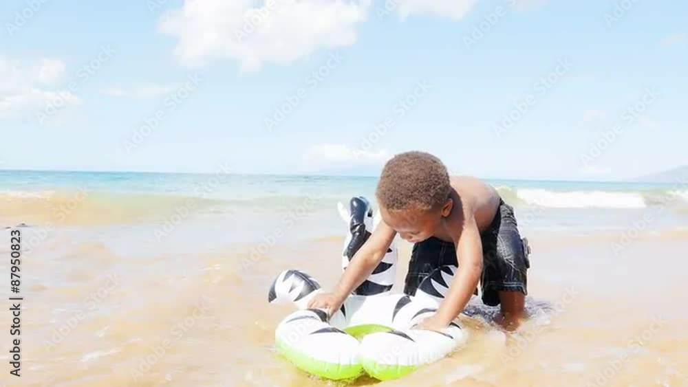Black toddler playing in the ocean with an inflatable toy Black toddler playing in the ocean with an inflatable toy