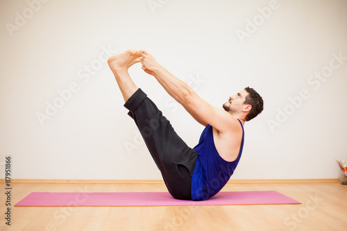 Young man doing a boat yoga pose
