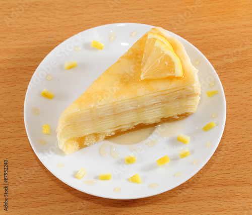 Lemon crepe cake with honey on plate.