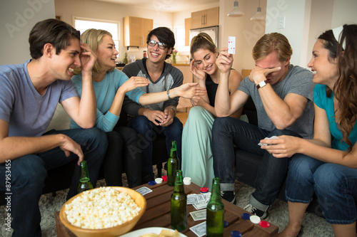 Game night poker playing friends loser embarrassed and winner celebrates at party