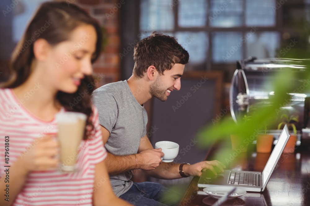 Smiling young man sitting at bar and using laptop Smiling young man sitting at bar and using laptop