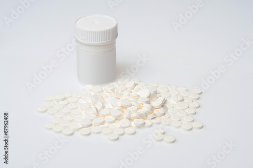 White pills lying near a white bottle photo