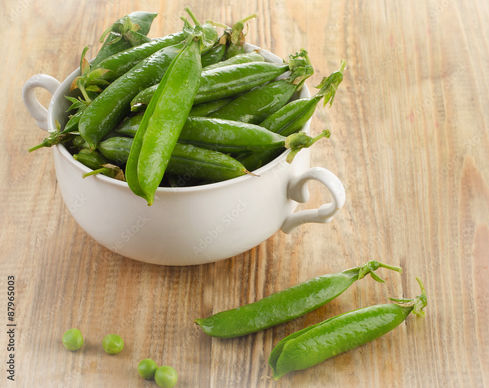 Green peas in white bowl on a wooden background. Green peas in white bowl on a wooden background.