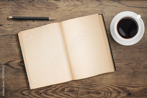 Open diary with pen and coffee cup on old wooden table photo