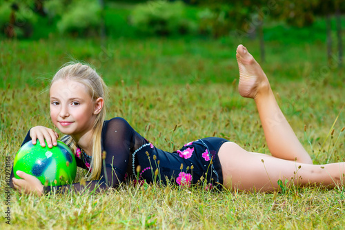 outdoor portrait of young cute little girl gymnast training with