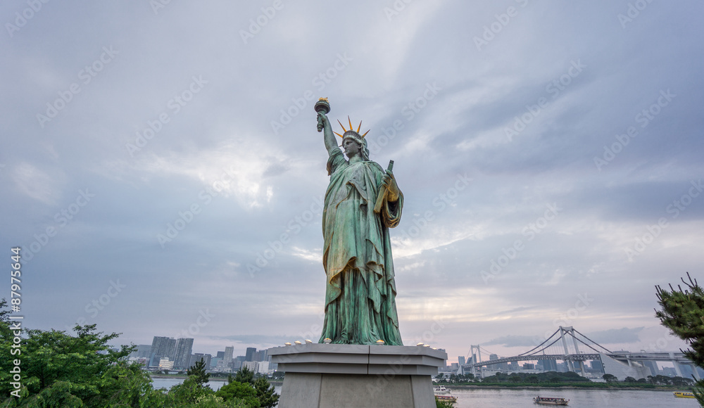 Obraz premium Statue of Liberty and Rainbow bridge in Odaiba at sunset