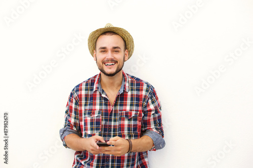 Young man with hat smiling with cell phone