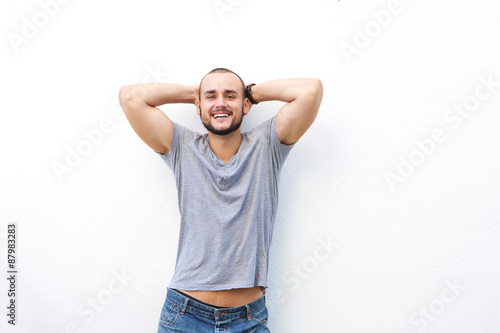 Happy young man smiling with hands behind his head