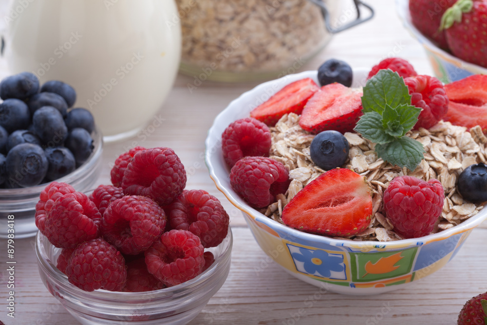 Breakfast - berries, fruit and muesli on white wooden Breakfast - berries, fruit and muesli on white wooden