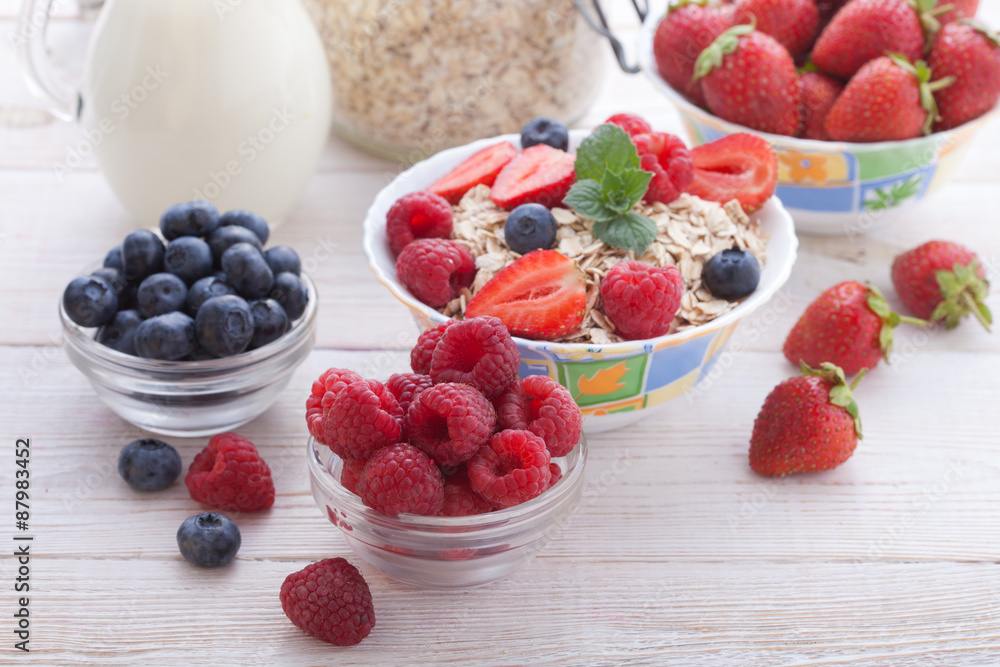 Breakfast - berries, fruit and muesli on white wooden Breakfast - berries, fruit and muesli on white wooden