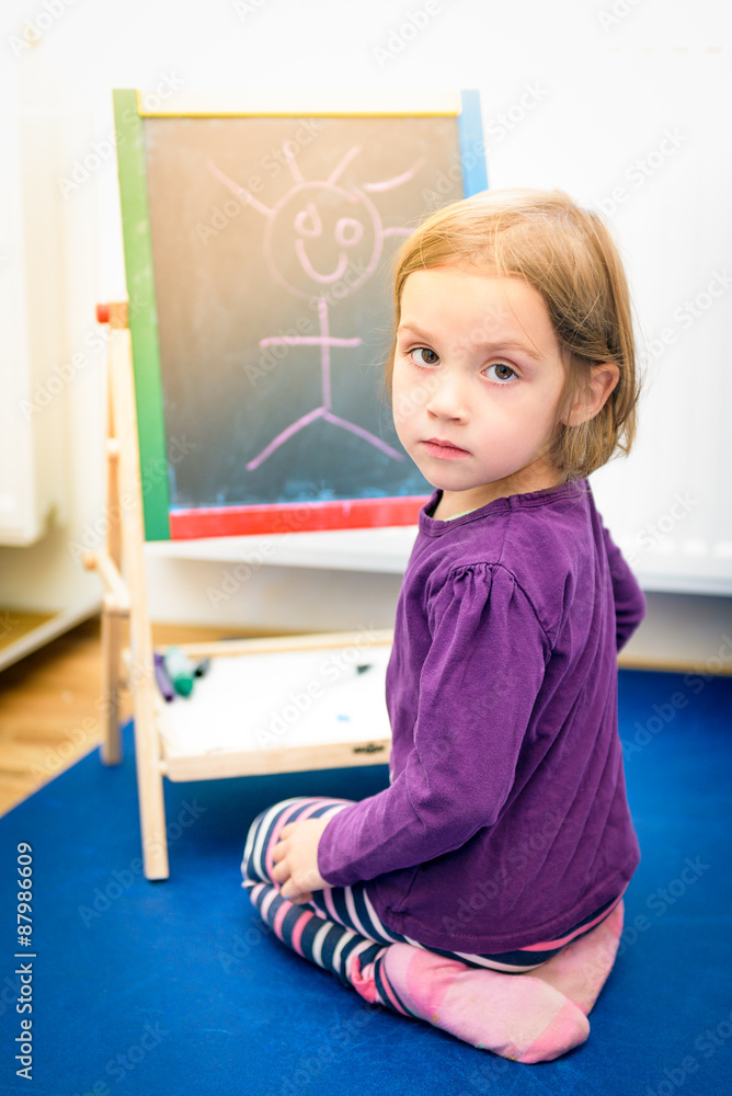 Little child is drawing with color chalk on the chalk board Little child is drawing with color chalk on the chalk board