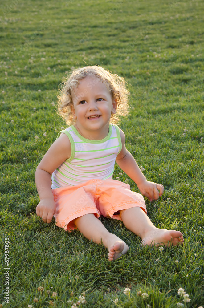 Adorable child sittng barefoot on the grass Adorable child sittng barefoot on the grass