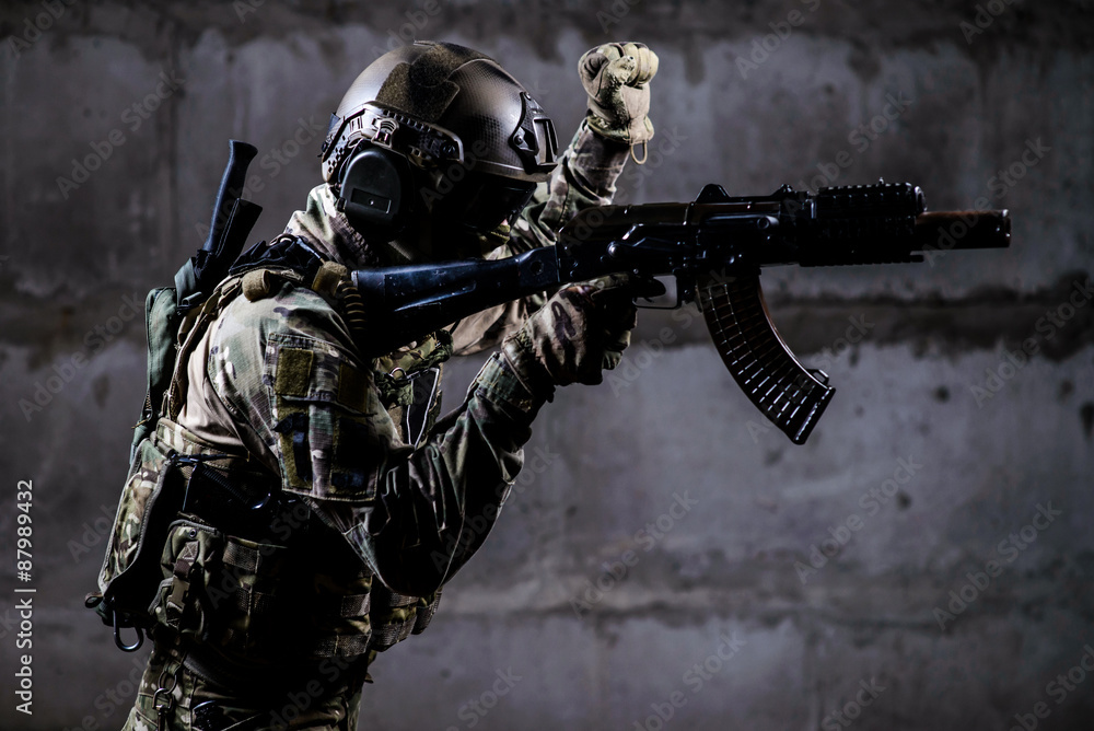 Fototapeta premium Armed soldier in camouflage with weapon shows special signal
