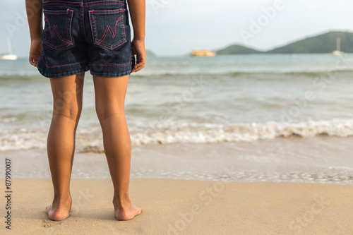 Legs of children stand on the beach