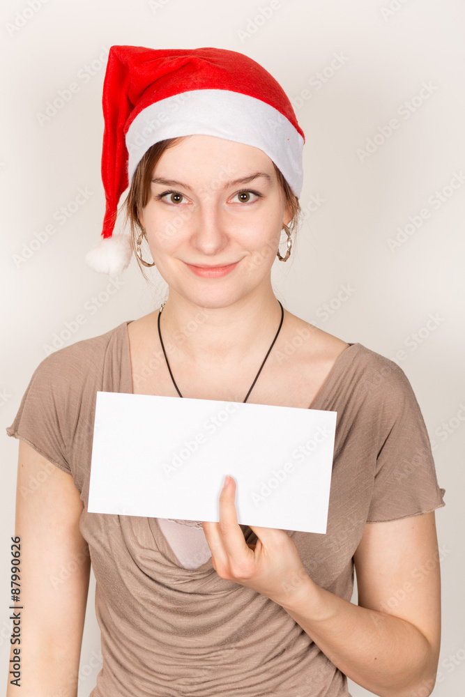 Junge Dame mit Weihnachtsmannmütze hält weißes Schild mit Platz für Text