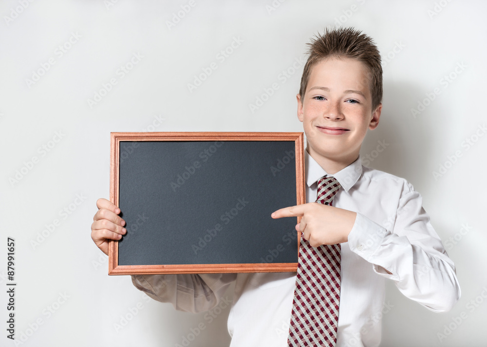 Smiling schoolboy pointing finger at empty chalkboard Smiling schoolboy pointing finger at empty chalkboard