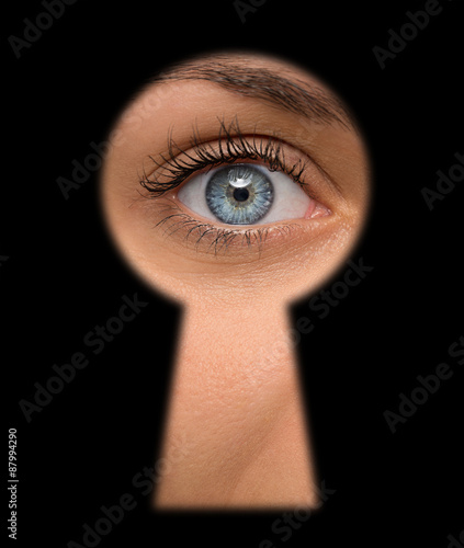 Canvas Print Curious female peeking through a keyhole