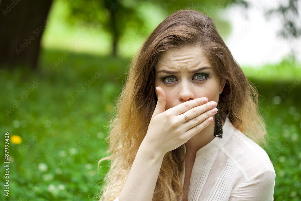 Young beautiful girl covers her mouth with his hand Young beautiful girl covers her mouth with his hand