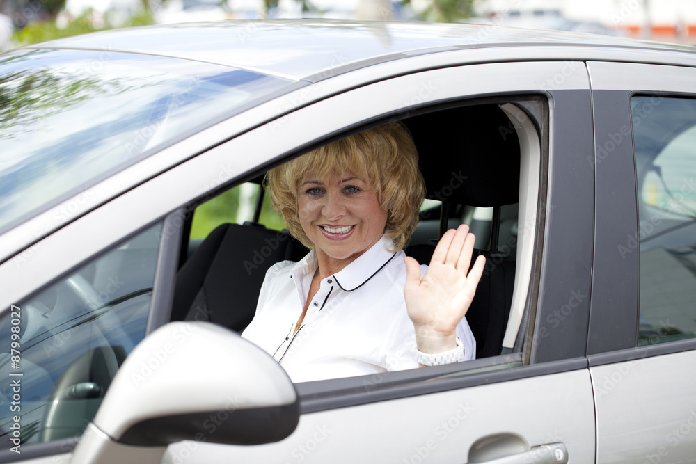 Old happy elderly driver woman 55-60 years in jacket Driving a C