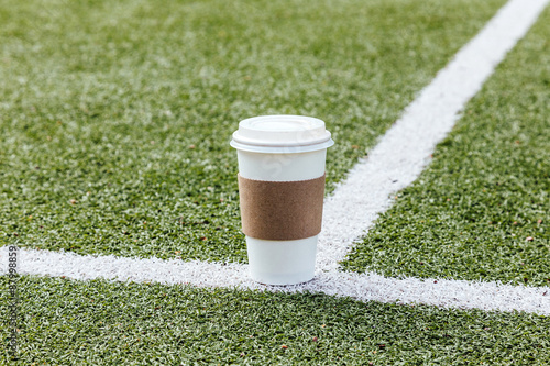 Blank coffee paper cup on football field