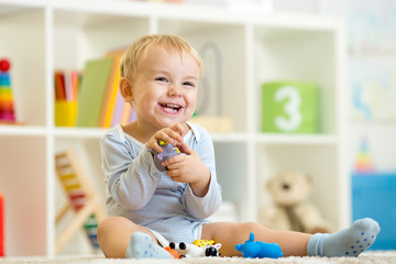 little child plays with toys animals