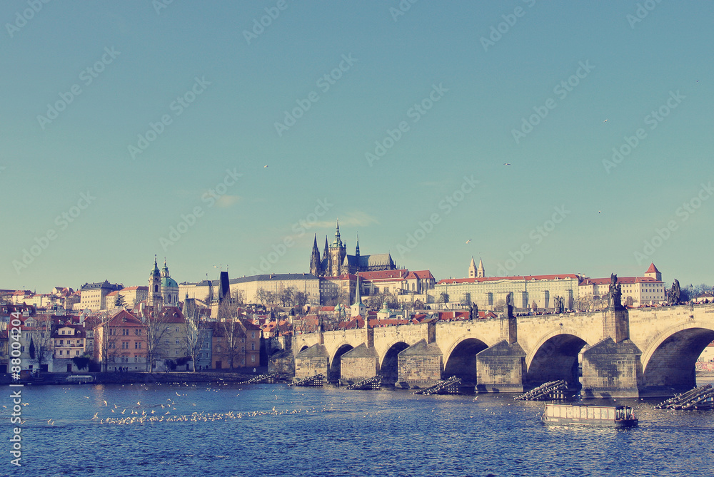 Charles' Bridge with Hradcany castle in the background in Prague, Czech Republic, on a sunny day. Image filtered in faded, washed out, retro style; nostalgic travel vintage concept.
