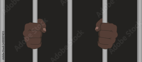 Black man fists in darkness holding prison bars