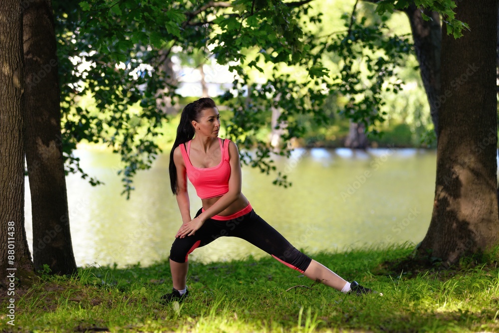 Beautiful young woman doing stretching exercise in park near river Beautiful young woman doing stretching exercise in park near river