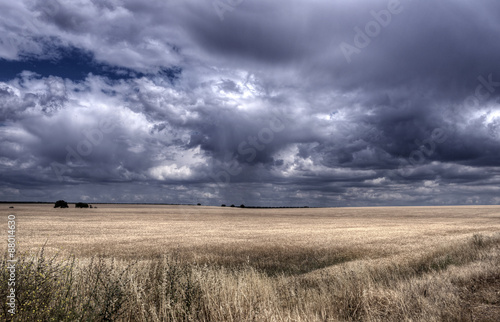 Campo de tierra laborable seco con nubes formando una tormenta