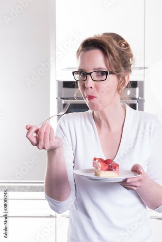 attractive woman in modern ktchen eating strawberry cake photo