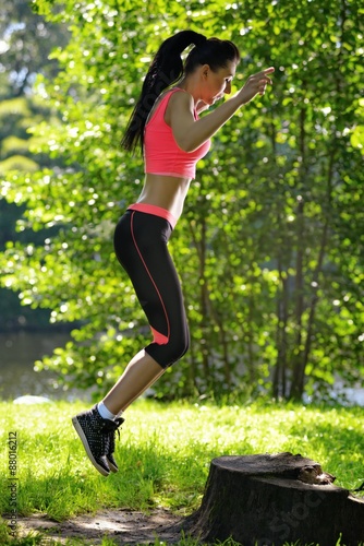 Beautiful woman fitness jumping at park on stub