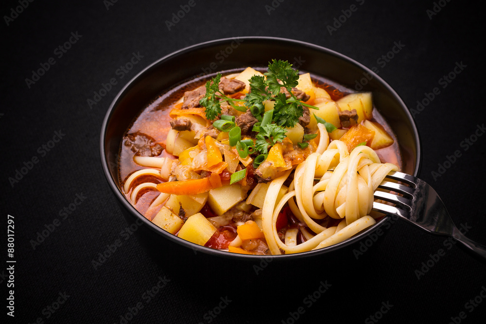 Uzbek noodle soup Lagman on black, close up