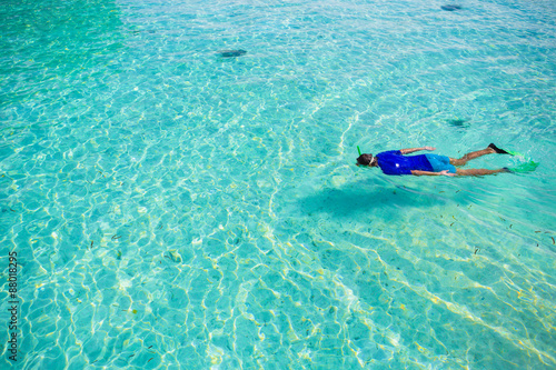 Young man snorkeling in clear tropical turquoise waters