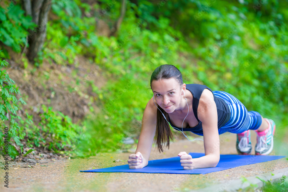 Young smiling woman doing sporty exercises outdoors