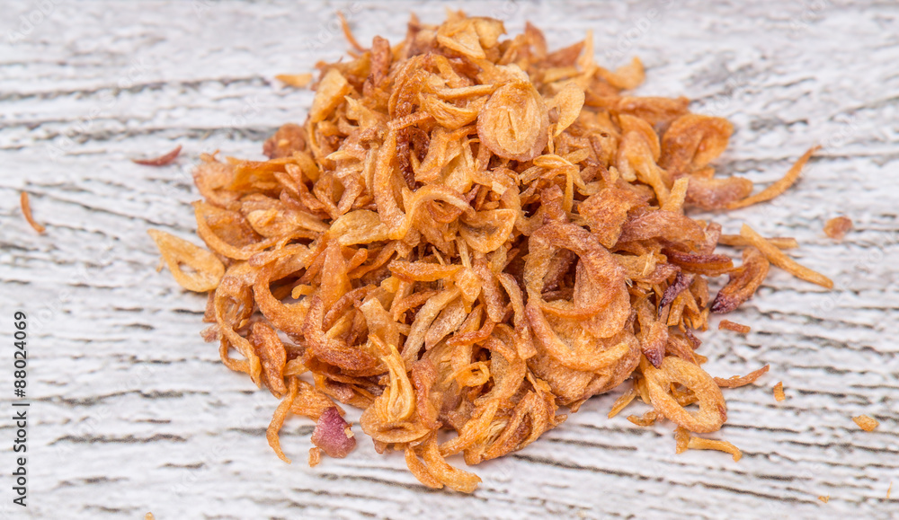 Deep fried shallots for garnishing over wooden background Deep fried shallots for garnishing over wooden background