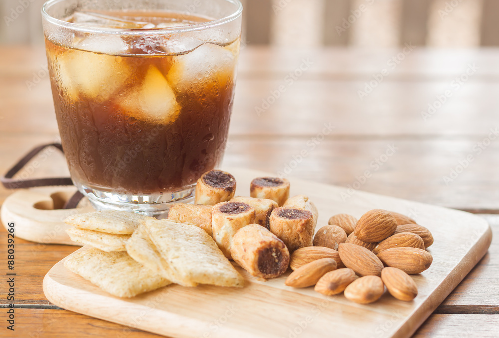 Glass of black iced coffee with some snack Glass of black iced coffee with some snack
