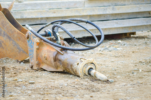 Industrial excavator jackhammer or drill unused on the dirty ground on a construction site in a close look with the cabls and oil dripping out photo