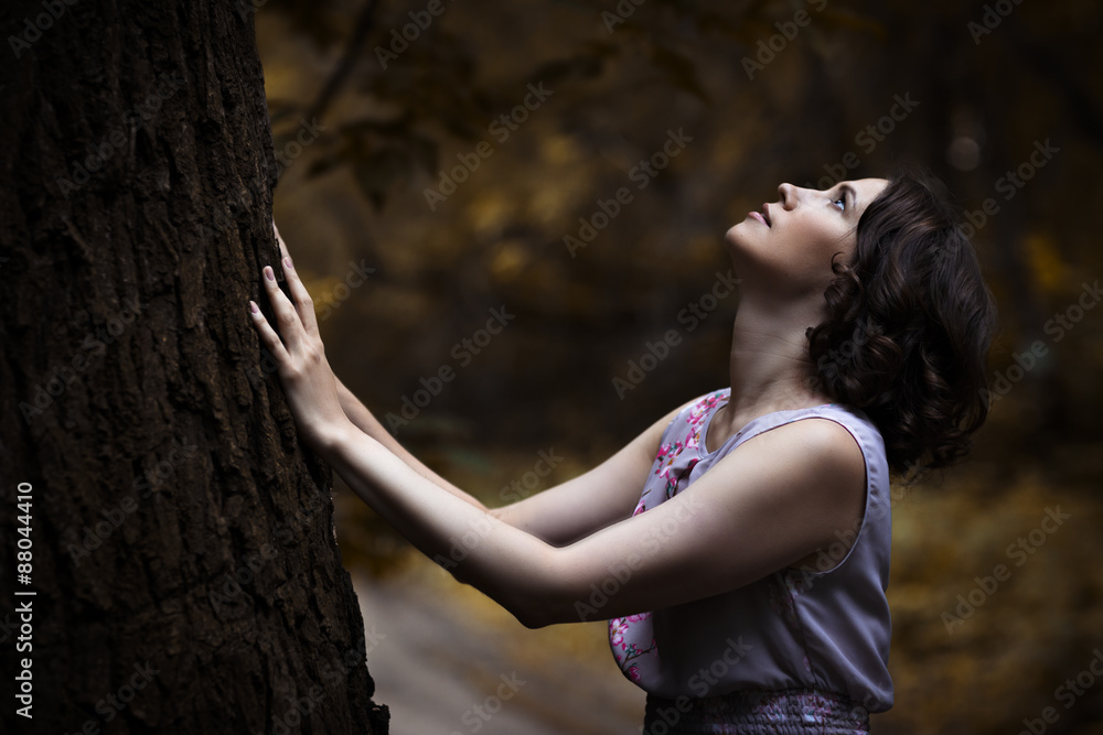 young woman standing at tree and looing up young woman standing at tree and looing up