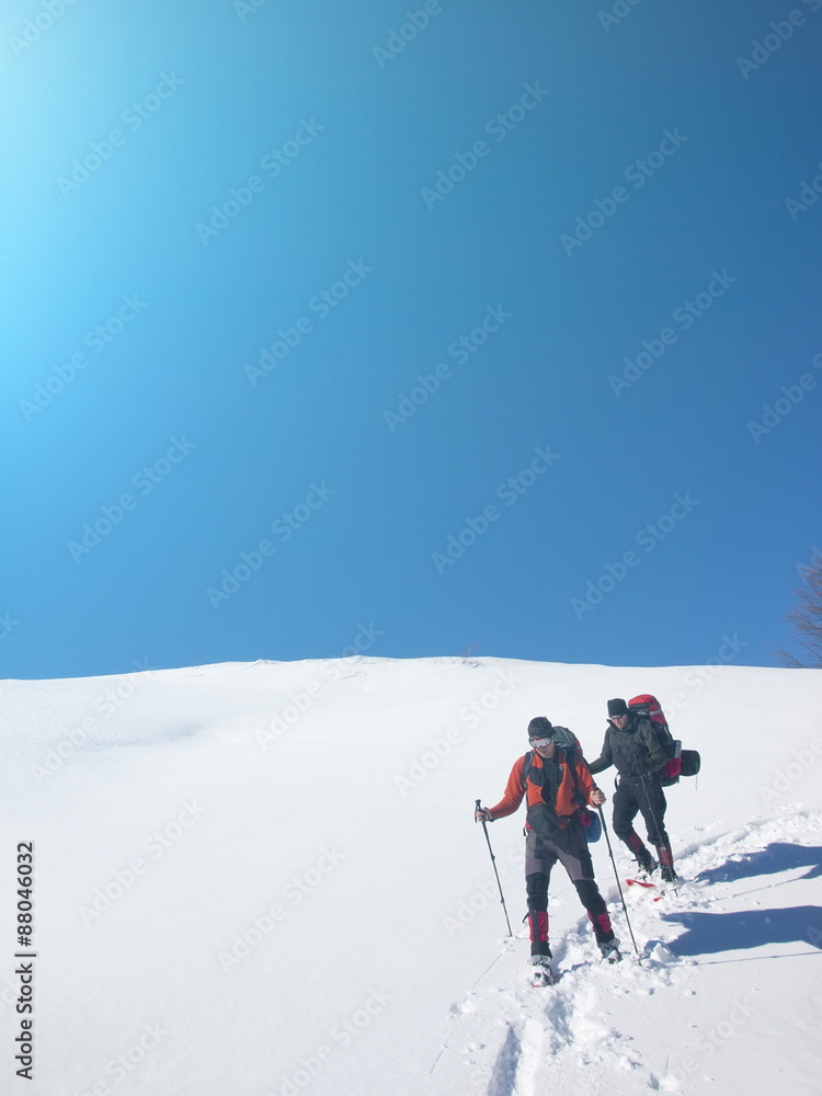 Men go snowshoeing in the mountains in the snow.