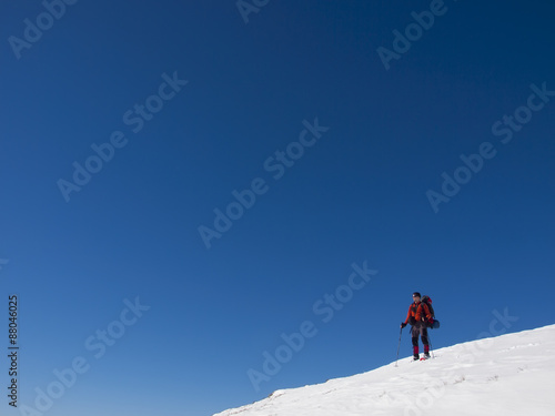 A man in snowshoes is in the mountains. © zhukovvvlad