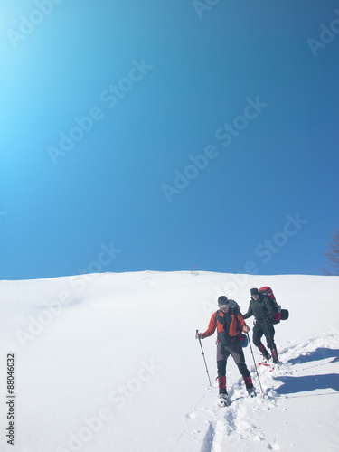 Men go snowshoeing in the mountains in the snow.